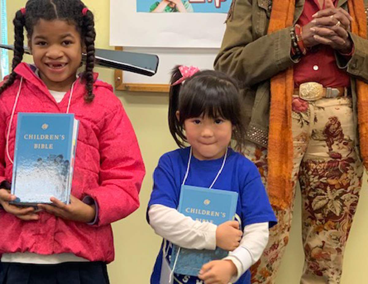 Two smiling girls holding their new children's Bibles