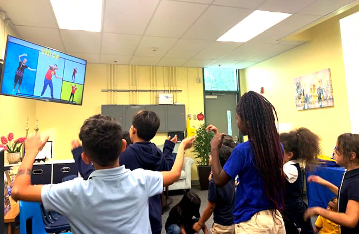 Children raising their hands during a Good News Club lesson